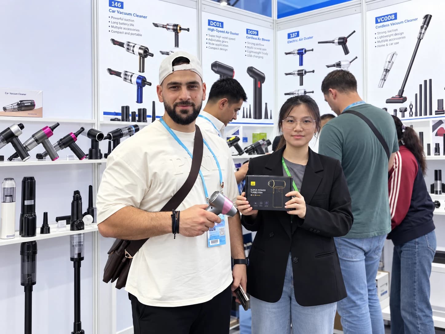 Customer holding an air duster beside a DRC team member holding its product box at the exhibition booth